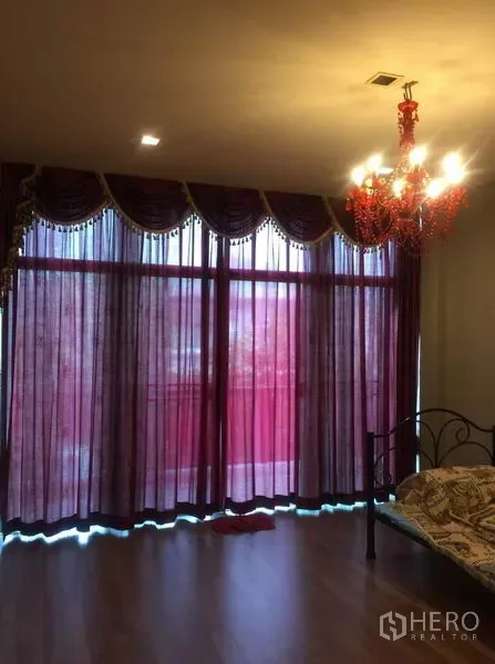 Detached House for sale in Pak Kret, Nonthaburi - Spacious bedroom with a red chandelier and full-height draped curtains.