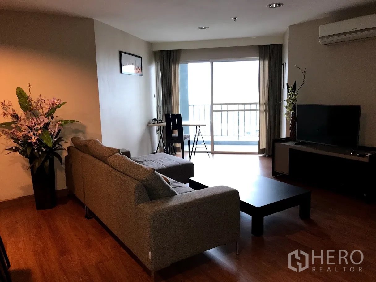 Condominium for rent in Huai Khwang, Bangkok - Living room featuring sofa set, TV console and balcony access for natural light.