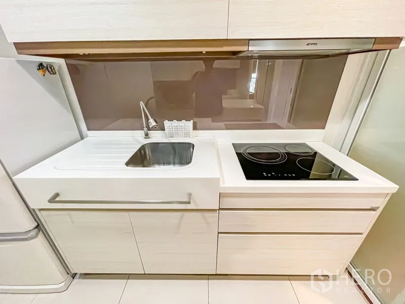 คอนโด ขาย - ภาพระยะใกล้ของครัว แสดงซิงก์ เตาเซรามิก และผนังกันเปื้อน