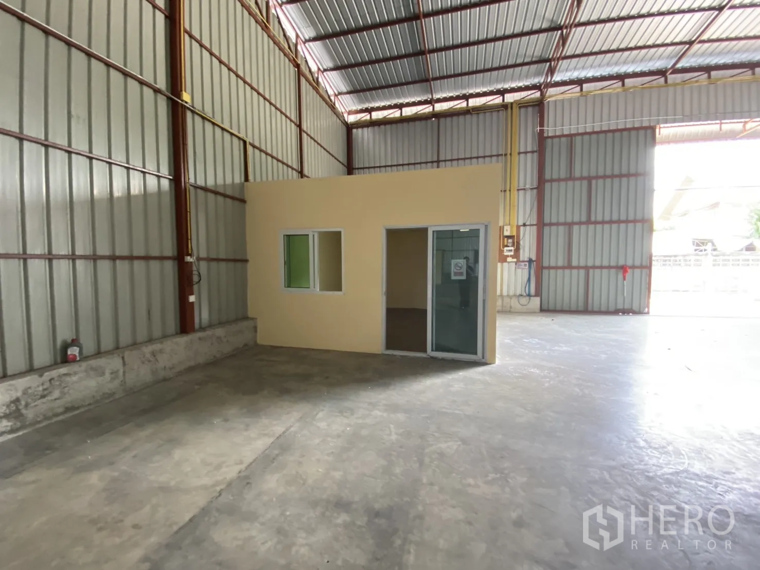 Warehouse for rent in Bueng Kum, Bangkok - Small office unit with windows and a sliding glass door within the warehouse.