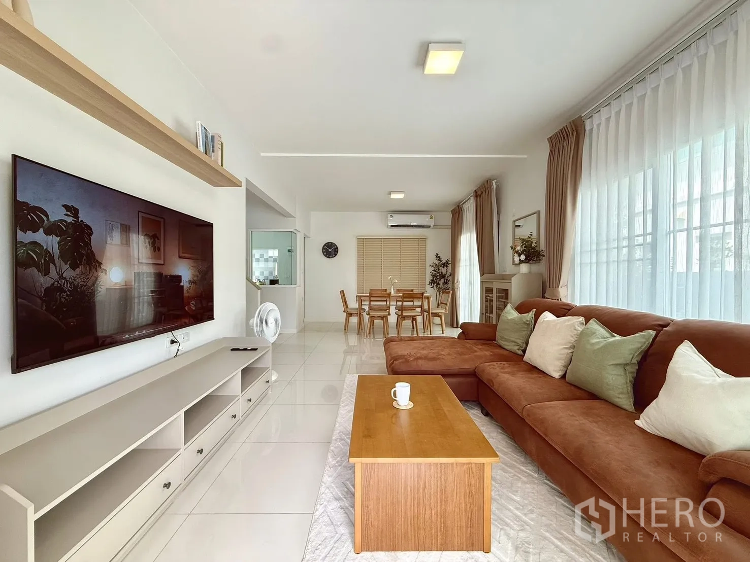 บ้านเดี่ยว for rent in Bang Phli, Samut Prakan - ห้องนั่งเล่นโปร่งสว่าง โซฟาเข้ามุมสีน้ำตาล ผ้าม่านทึบและโปร่ง พร้อมทีวีและมุมทานอาหาร