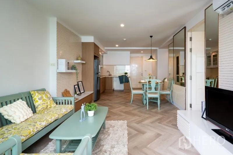 Condominium for sale in Watthana, Bangkok - Bright living and dining space with mint furniture, open kitchen and herringbone floors.