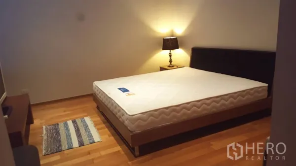 公寓 出租或出售在Khlong Toei, Bangkok - 舒适卧室，双人床、床头灯与木地板。