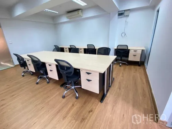 Office Space for rent in Khlong Toei, Bangkok - Open-plan office with long workstations, ergonomic chairs, wood flooring, and wall-mounted air conditioning.