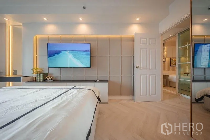 คอนโด ให้เช่า - ห้องนอนหลักผนังตกแต่งพร้อมทีวีติดผนังและไฟซ่อนโทนอุ่น