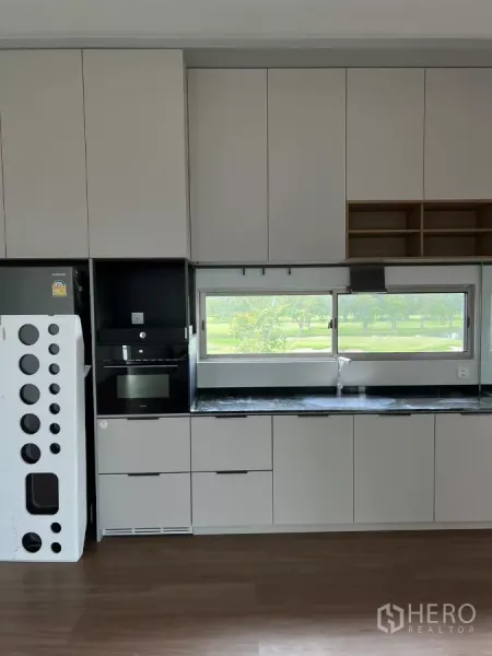 独立式住宅 出租在Saphan Sung, Bangkok - 简约一体化厨房，哑光柜体、黑色台面与面向绿景的窗户。