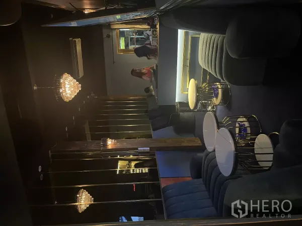 店屋 出租在Watthana, Bangkok - 室内休闲区，吊灯、镜面墙、沙发与圆形小桌。