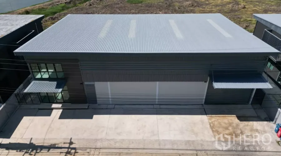 Factory for rent in Bang Bo, Samut Prakan - Aerial view of a modern grey factory with metal roof, large roller doors and a wide concrete loading apron.