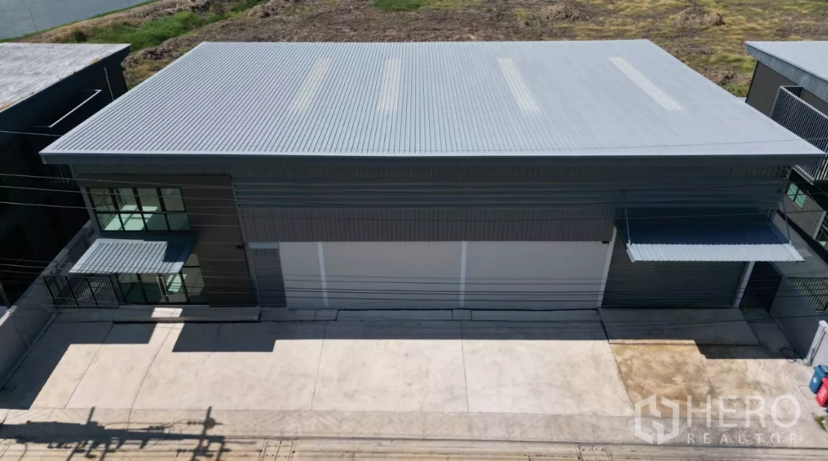 Factory for rent in Bang Bo, Samut Prakan - Aerial view of a modern grey factory with metal roof, large roller doors and a wide concrete loading apron.