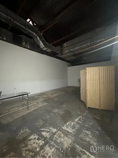 พื้นที่ขายปลีก ให้เช่า - มุมมองพื้นที่โล่งโชว์ท่อแอร์ ผนังสีขาว และฉากกั้นแบบพับได้