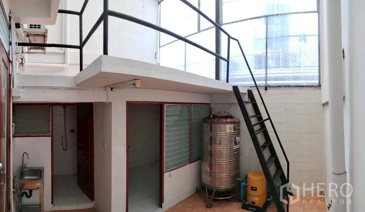 Home Office for rent in Watthana, Bangkok - Utility area with mezzanine platform, metal stairs, water tank, sink, and windows.