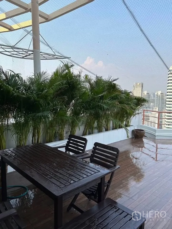 Condominium for rent or sale in Yan Nawa, Bangkok - Outdoor dining set on large terrace lined with palms and skyline backdrop.