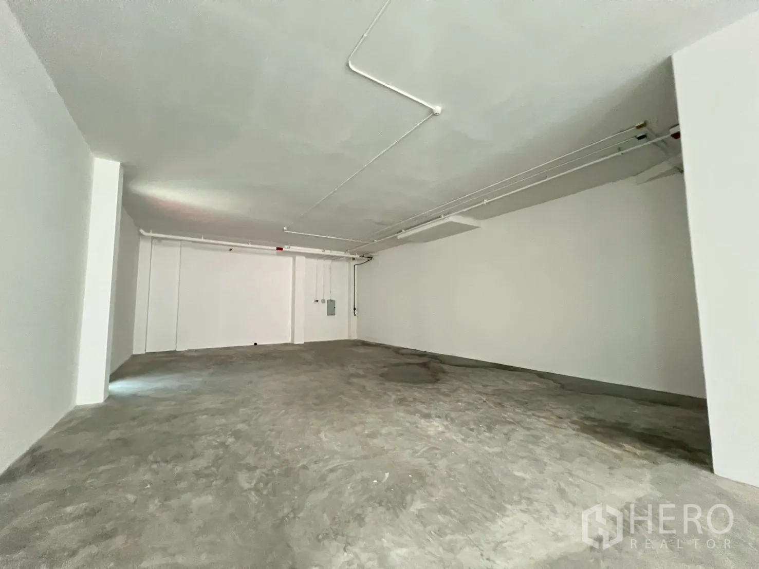 Retail Space for rent in Khlong Toei, Bangkok - Back area of the retail unit showing exposed ceiling services and smooth concrete flooring.