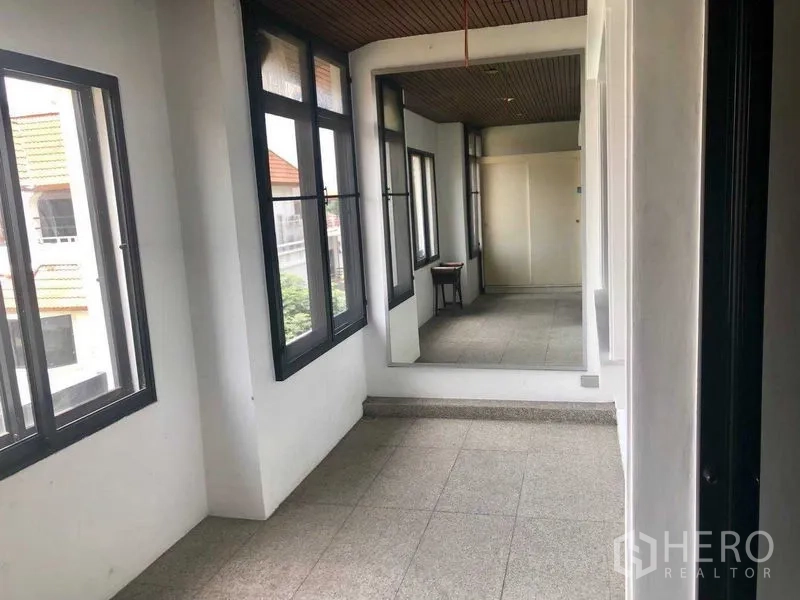 Townhouse for rent in Khlong Toei, Bangkok - Bright hallway with multiple windows, ceiling detail, and a full‑length wall mirror.
