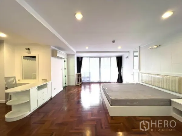Condominium for rent in Watthana, Bangkok - Spacious bedroom with parquet floor, built-in vanity, and sliding door to the balcony.