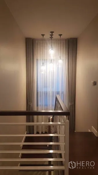 独立式住宅 出租在Saphan Sung, Bangkok - 楼梯平台配吊灯、纱帘与白色扶手。