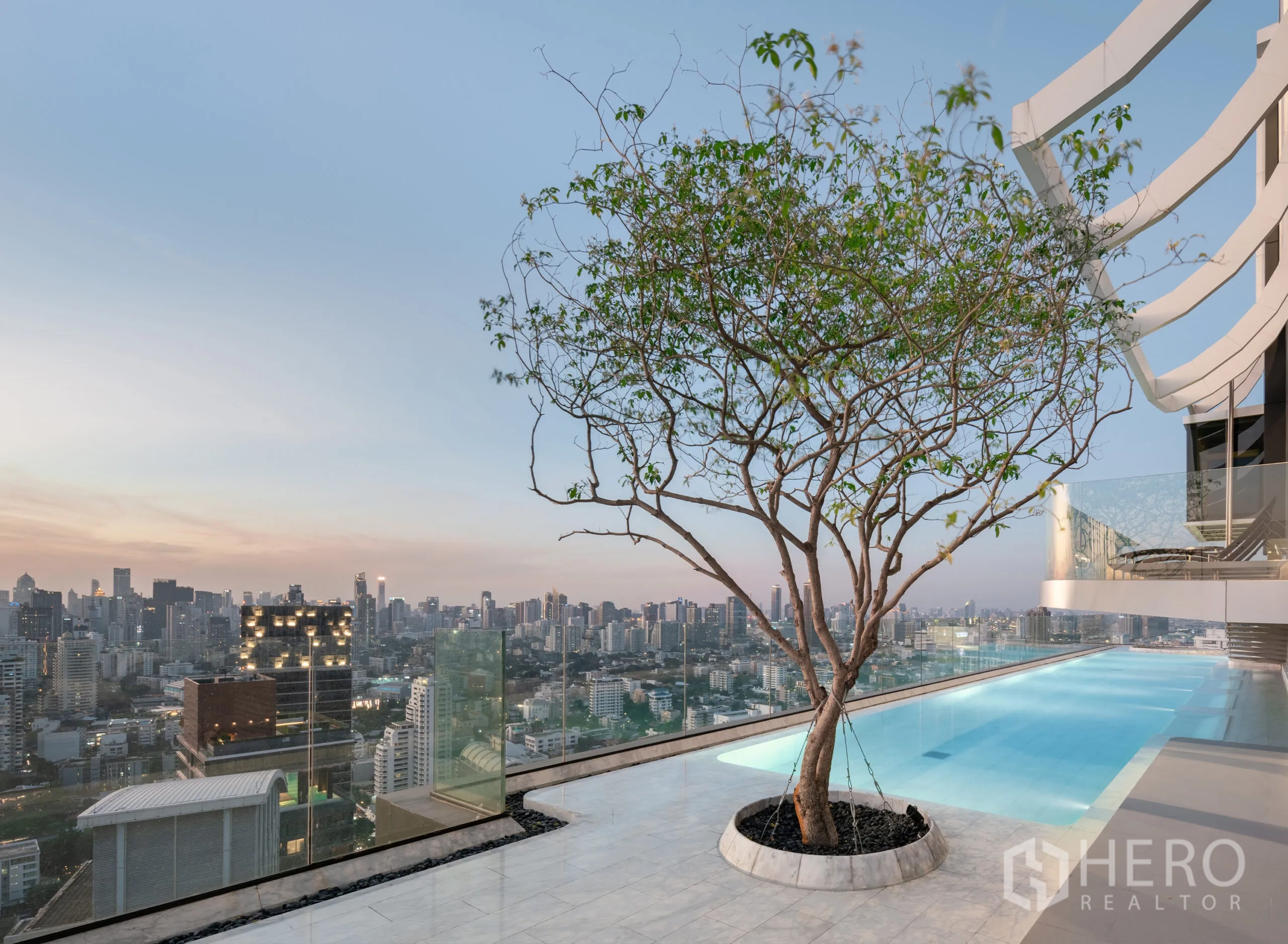 公寓 for rent in Watthana, Bangkok - 屋顶无边际泳池配玻璃护栏与景观树，可眺望城市天际线全景。