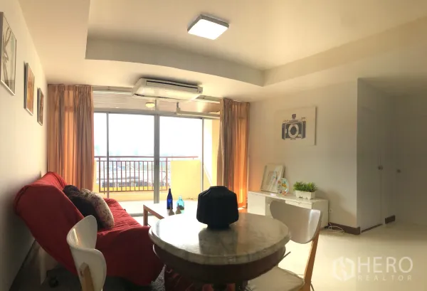 公寓 出租或出售在Khlong Toei, Bangkok - 明亮客厅，红色沙发、圆形餐桌，推拉玻璃门通往带城市景观的阳台。