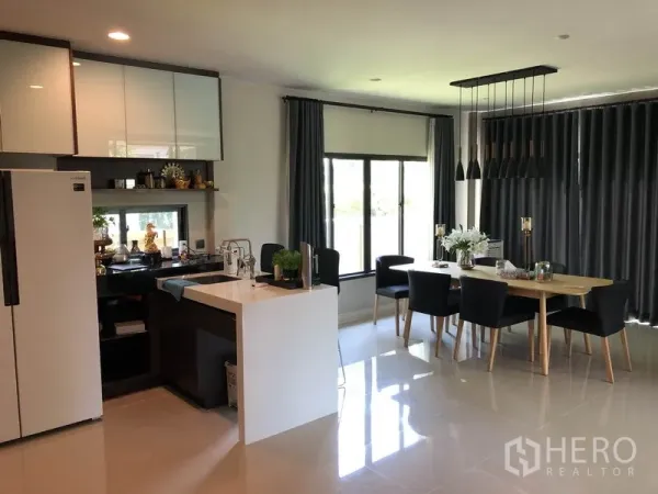 Detached House for rent in Bang Kapi, Bangkok - Bright kitchen with island and cabinets beside a dining area and full-height curtains.