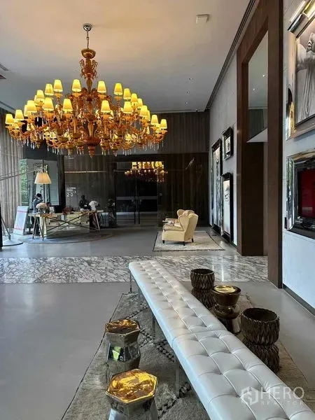 公寓 出租在Watthana, Bangkok - 优雅大堂视角，白色软包长凳、吊灯与落地玻璃。