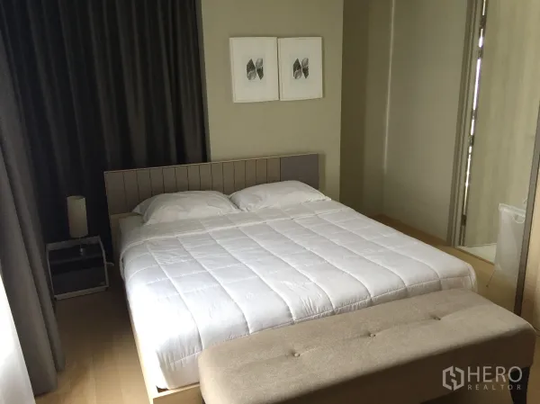 Condominium for rent in Watthana, Bangkok - Primary bedroom featuring a large bed, bench and blackout curtains.