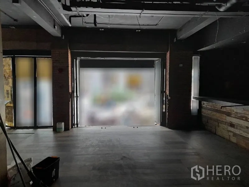 店屋 出租 - 一层店铺空间，宽阔临街入口，砖柱、深色地板与外露天花。