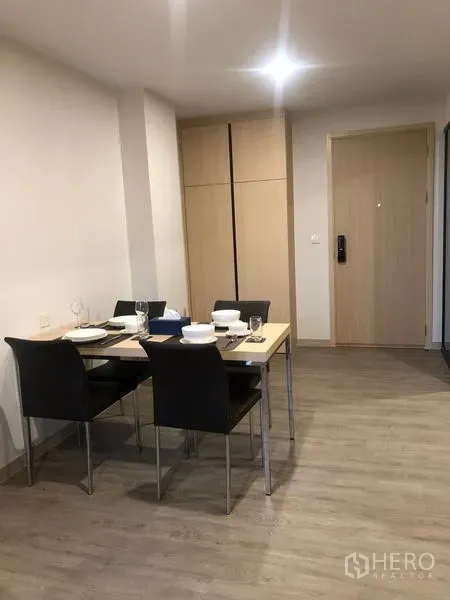 Condominium for rent or sale in Yan Nawa, Bangkok - Entry corridor with dining table and tall built-in wardrobe over wood-look flooring.
