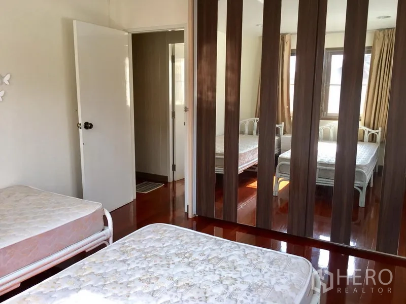 Detached House for rent in Khlong Toei, Bangkok - Second bedroom with twin beds and mirrored wardrobe panels reflecting natural light.