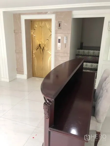 Shophouse for rent or sale in Chatuchak, Bangkok - Lobby area showing gold-finished elevator doors beside a dark wood reception counter.