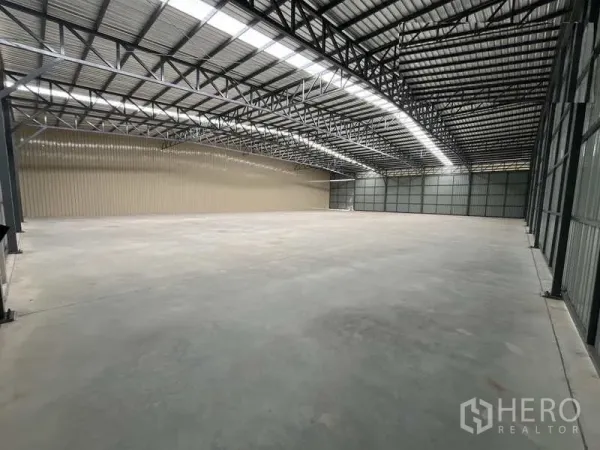 Warehouse for rent or sale in Pak Kret, Nonthaburi - Column-free storage hall with metal cladding walls and long roof lights for natural illumination.