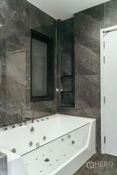 บ้าน ขายในSai Mai, Bangkok - ห้องน้ำกรุหินอ่อนพร้อมอ่างจากุซซี่สีขาวและหน้าต่างกรอบดำ