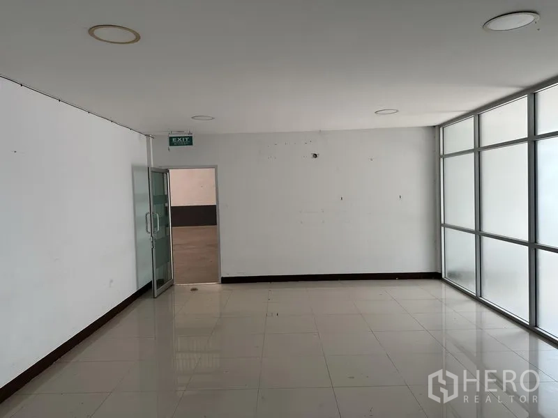 Warehouse for rent in Samut Prakan - Ground-floor office room with frosted glass partition and exit door.