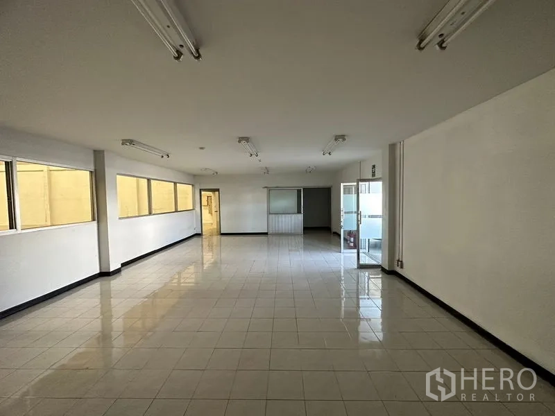 Factory for rent in Si Racha, Chon Buri - Bright tiled office room with fluorescent lighting, glass entrance and partition windows.