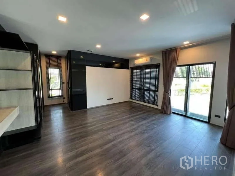 Detached House for rent or sale in Bang Phli, Samut Prakan - Spacious living area with wood floors, sliding doors to the garden and window blinds.