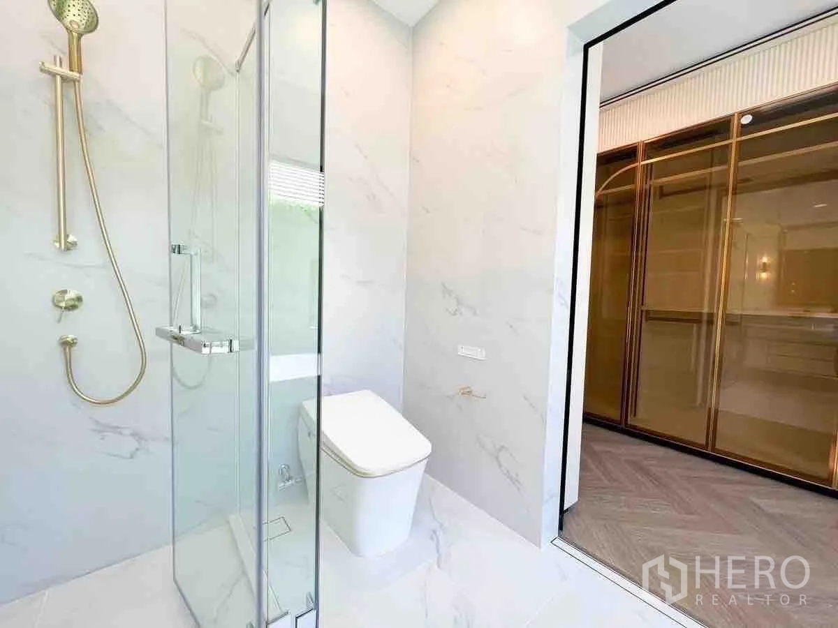 Detached House for rent or sale in Saphan Sung, Bangkok - Modern bathroom with glass shower, gold fixtures and marble-look tiles
