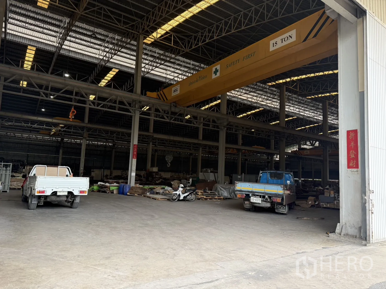 Factory for rent in Bang Phli, Samut Prakan - Workshop corner inside the warehouse with a small office box, vehicles and concrete floor.