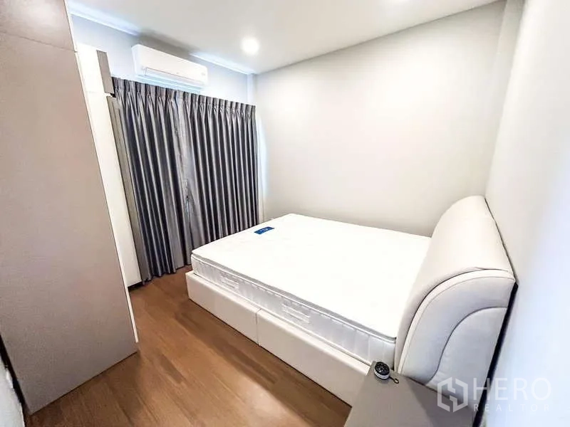 Detached House for rent in Bang Phli, Samut Prakan - Compact bedroom with double bed, grey curtains, wood floor and wall-mounted air conditioner.