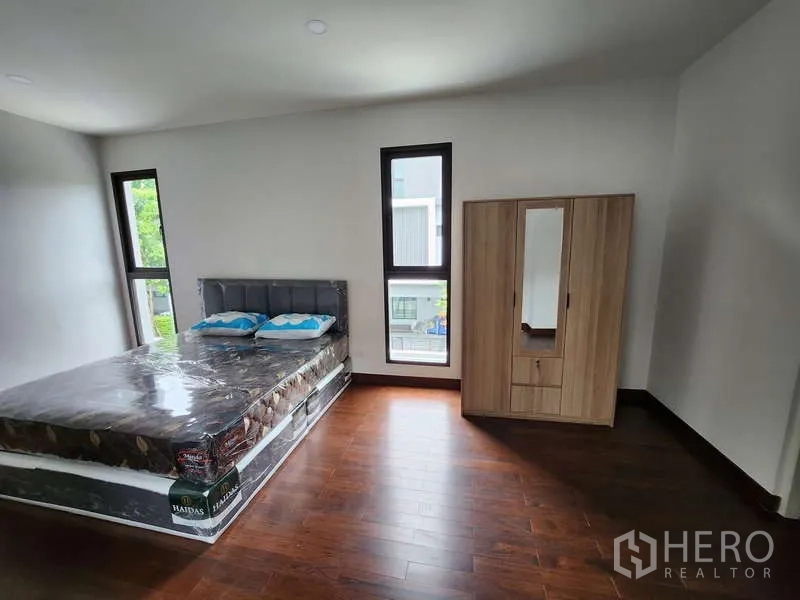 Detached House for rent in Wang Thonglang, Bangkok - Large bedroom with wood floors, double bed and freestanding wardrobe.