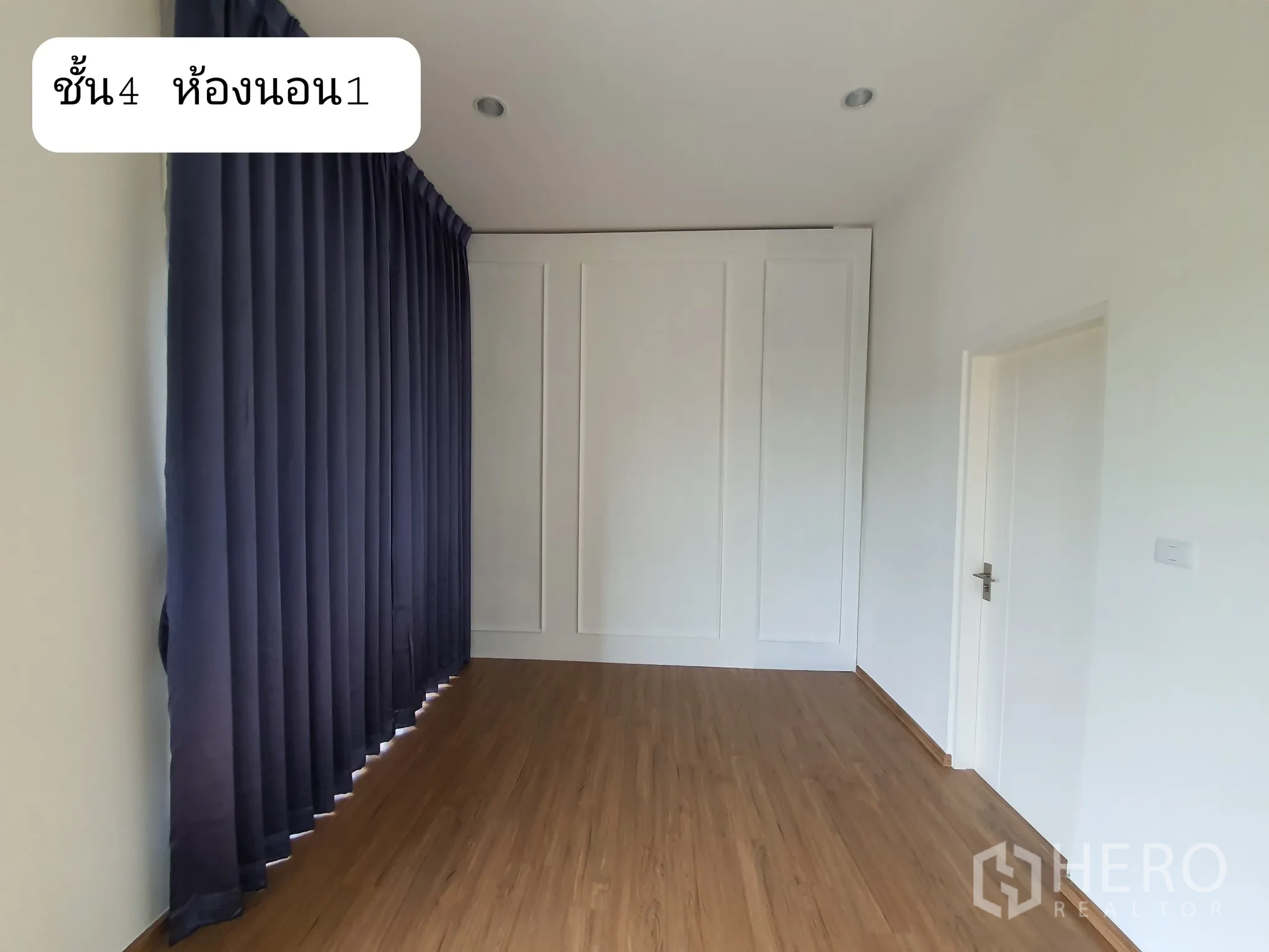 Home Office for rent or sale in Prawet, Bangkok - Upper bedroom with full-height dark curtains, paneled feature wall and wood flooring.