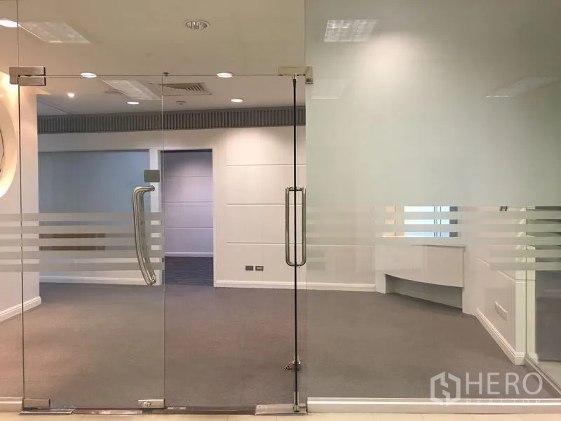 办公空间 出租在Chatuchak, Bangkok - 入口双扇玻璃门带磨砂条纹，通向铺地毯的办公区。