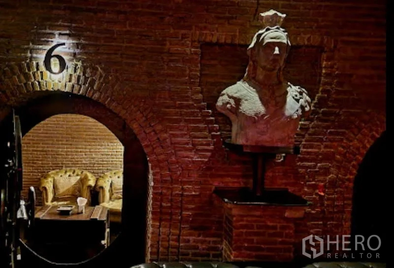 零售空间 出租 - 砖拱空间内的休息区，石雕半身像与纽扣沙发，氛围昏暗如私酒吧。