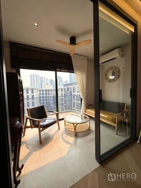 Condominium for rent in Watthana, Bangkok - Glass-enclosed balcony sunroom with lounge chairs and city view.