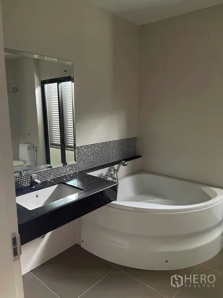 บ้าน ขายในLat Krabang, Bangkok - ห้องน้ำมีอ่างอาบน้ำมุม เคาน์เตอร์ท็อปหินสีดำ และกระจกบานใหญ่