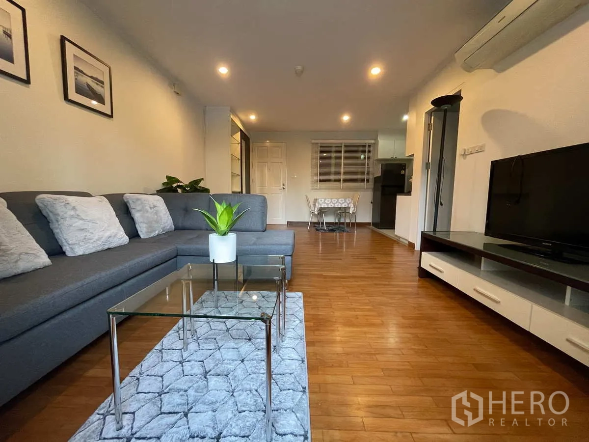 Condominium for rent in Watthana, Bangkok - Spacious living room view toward dining set and kitchen with wood floors.