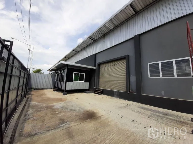 工厂 出租在Lam Luk Ka, Pathum Thani - 宽阔的混凝土场地，配安保大门、小型办公室与卷帘装卸口。