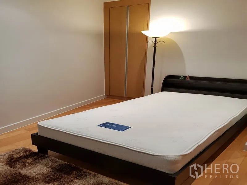 คอนโด ให้เช่าหรือขายในKhlong Toei, Bangkok - ห้องนอนที่สองสไตล์มินิมอล เตียงเฟรมไม้ ตู้เสื้อผ้า และโคมไฟพื้น