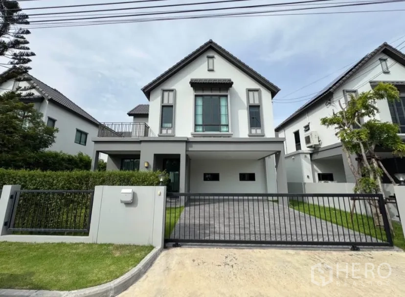 บ้านเดี่ยว for rent or sale in Lat Krabang, Bangkok - ด้านหน้าบ้านเดี่ยวสไตล์โมเดิร์น พร้อมประตูรั้ว โรงจอดรถ ทางรถเข้า และสนามหญ้าเรียบร้อย