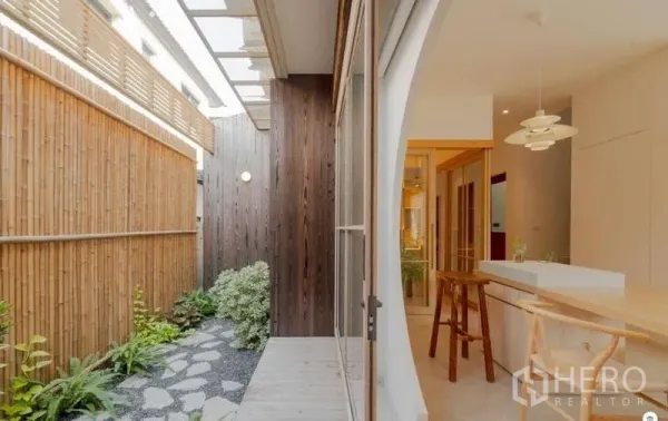 独立式住宅 出售在Bang Phli, Samut Prakan - 侧院带竹篱与踏石小径，推拉玻璃门通向厨房