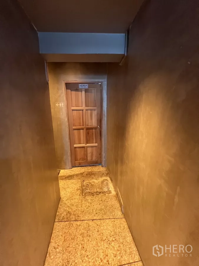 อาคารพาณิชย์ ให้เช่าในWatthana, Bangkok - โถงทางเดินแคบไปยังประตูไม้ของห้องน้ำและพื้นที่บริการ.