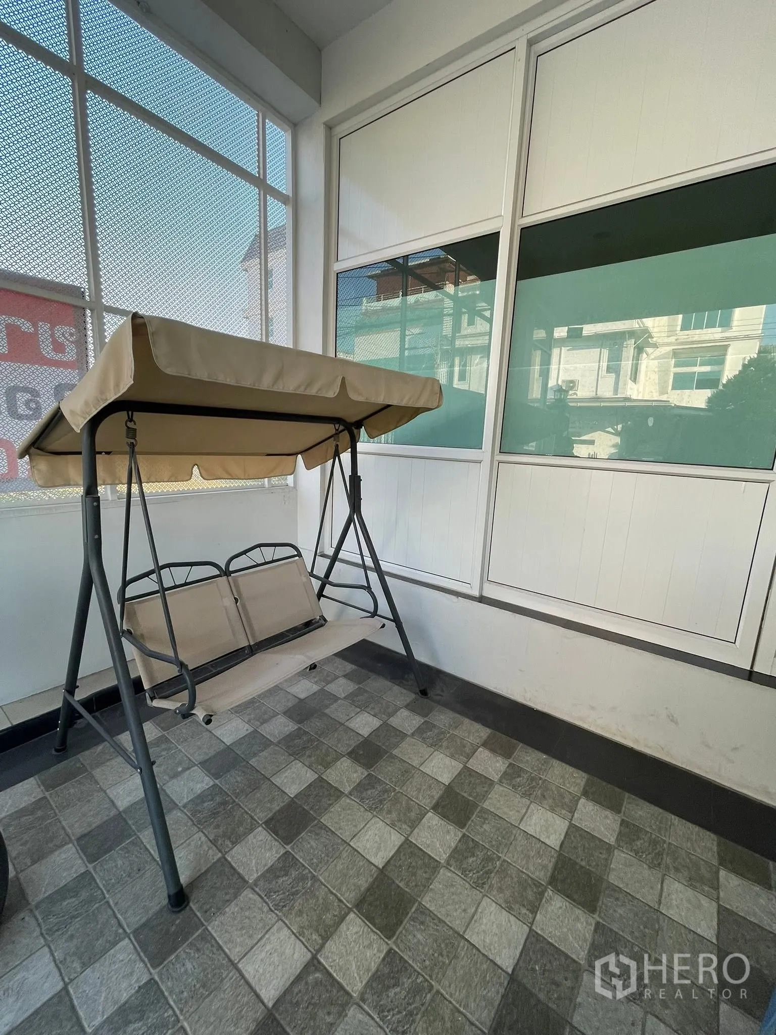 Detached House for rent or sale in Lam Luk Ka, Pathum Thani - Covered porch with a swing bench on checkered floor tiles.